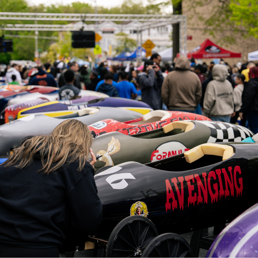 Side view of a row of over a dozen soap box cars