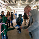 Acting Deputy Chancellor for Operations, Kevin Moran, handing a planner to a student during the first day of the school year.