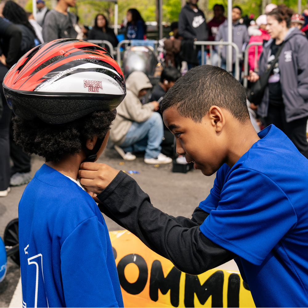 Student helping another student put on a helmet