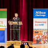 Suited Student at Podium (SoapboxNYC 2026)