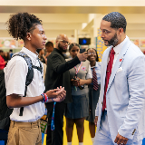 Side profile of a high school aged student (left) talking with Dr. Shawn Rux (right), senior executive director of the Office of New School Development and Design
