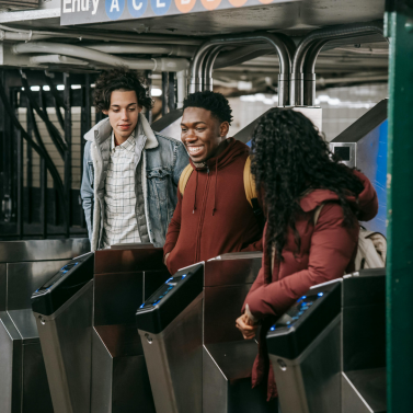 Three students walking through a subway turnstile.