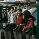 Three students walking through a subway turnstile.