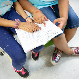 Image of two students reading a book together