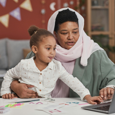 A woman and child are looking at a laptop