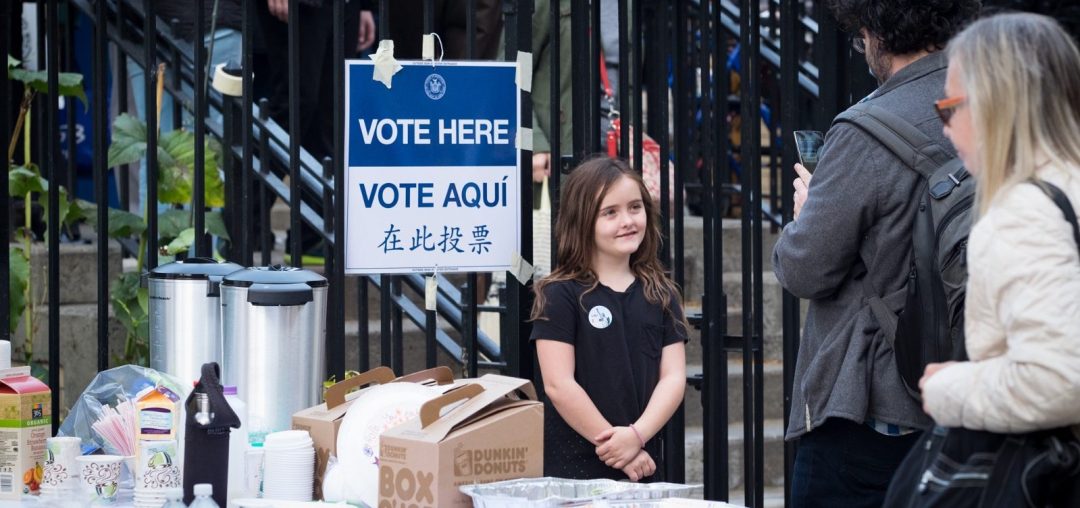 Young girl greeting potential voters arriving at a polling site at a City public school