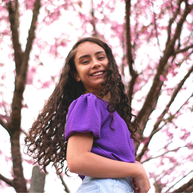 Close-up of a young girl smiling underneath cherry blossom trees