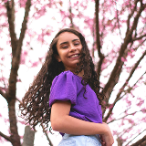Close-up of a young girl smiling underneath cherry blossom trees